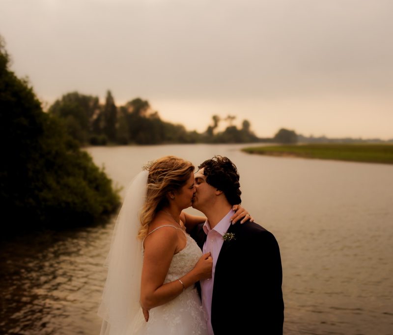 Couple kissing beside the Thames River near Oxford, romantic riverside wedding moment, featured in Oxfordshire wedding packages.
