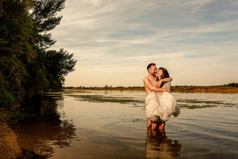 Bride and groom standing together in the River Thames after a spontaneous late evening swim with wedding guests