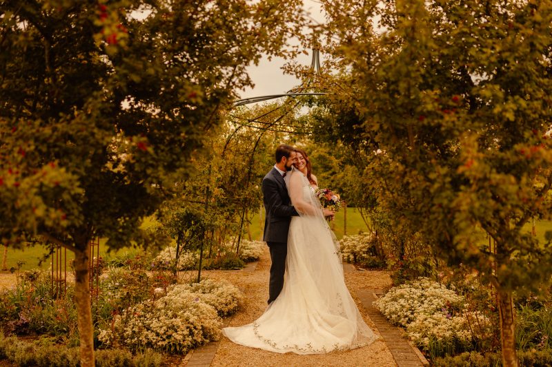 Bride and Groom hugging each other in the gardens of Stratton Court Barn Oxfordshire wedding photographed by Potters Instinct Photography