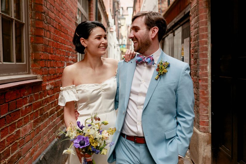 Bride and groom walking through the narrow streets of central Oxford during their micro wedding for relaxed natural portraits