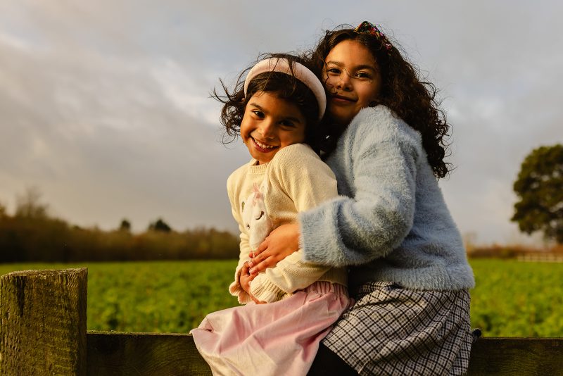 Family playing and walking together through long grass in the Oxfordshire countryside on a calm Sunday morning